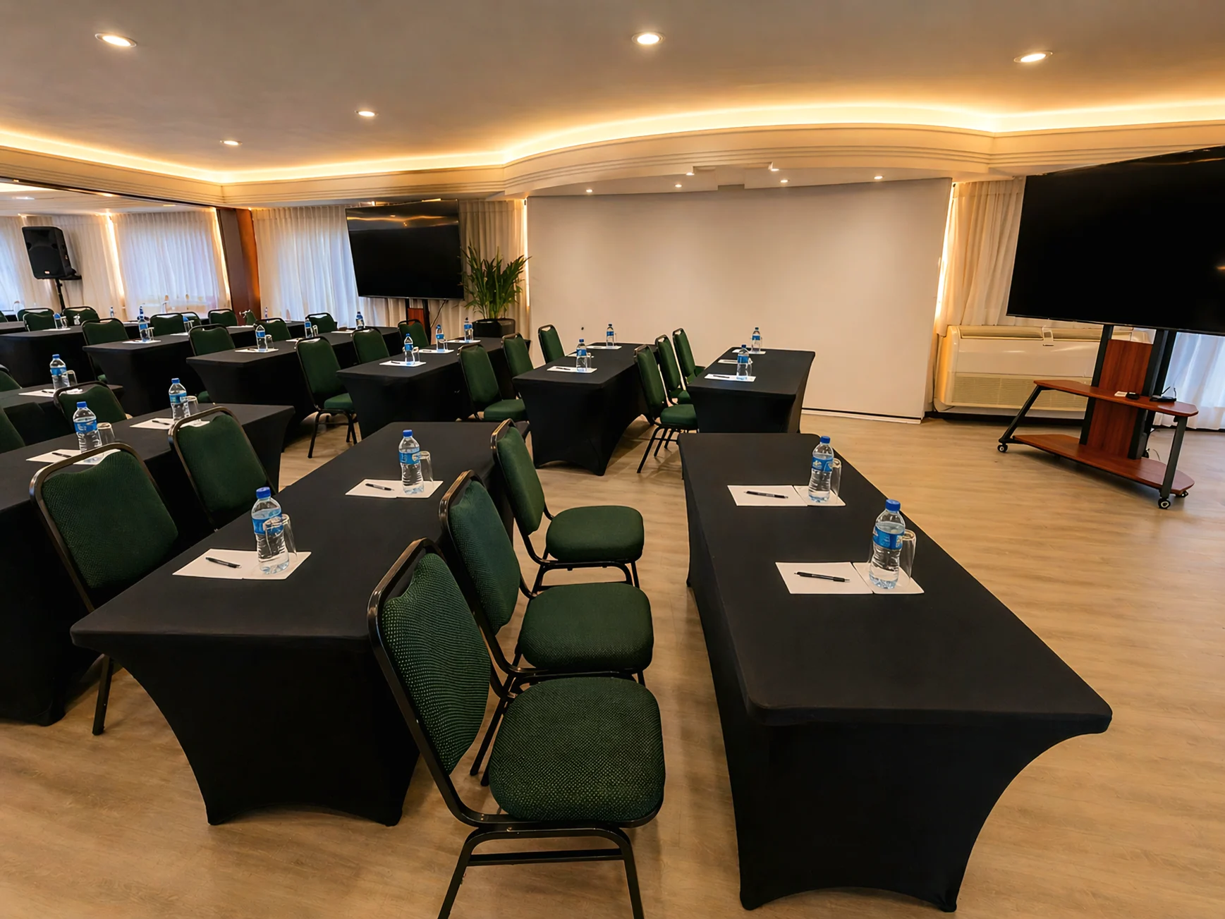 Sala de eventos do Santoni Hotel com mesas e cadeiras organizadas para encontro corporativo
